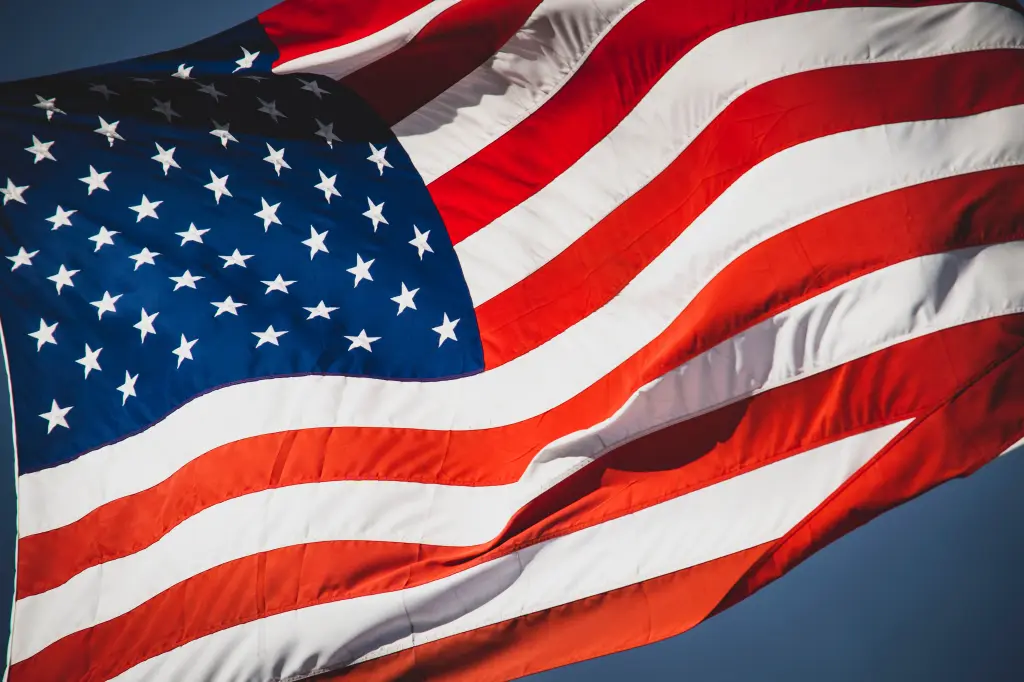 A close-up of the United States flag waving in the wind, showcasing its red and white stripes along with the blue field of white stars.